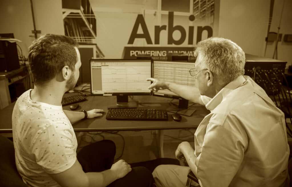 Arbin photo of 2 people at desk pointing at monitor